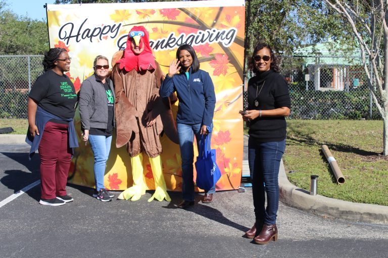 Event volunteers in front of a Thanksgiving photo backdrop
