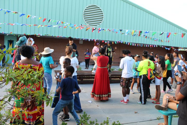 Families at an outdoor community celebration decorated with flags